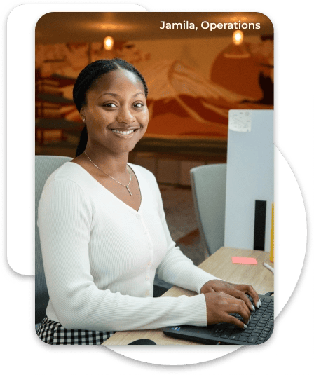 A woman on the operations team smiling at the camera while working on her laptop